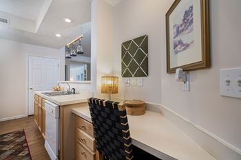 A kitchen with a white counter top and a black chair.